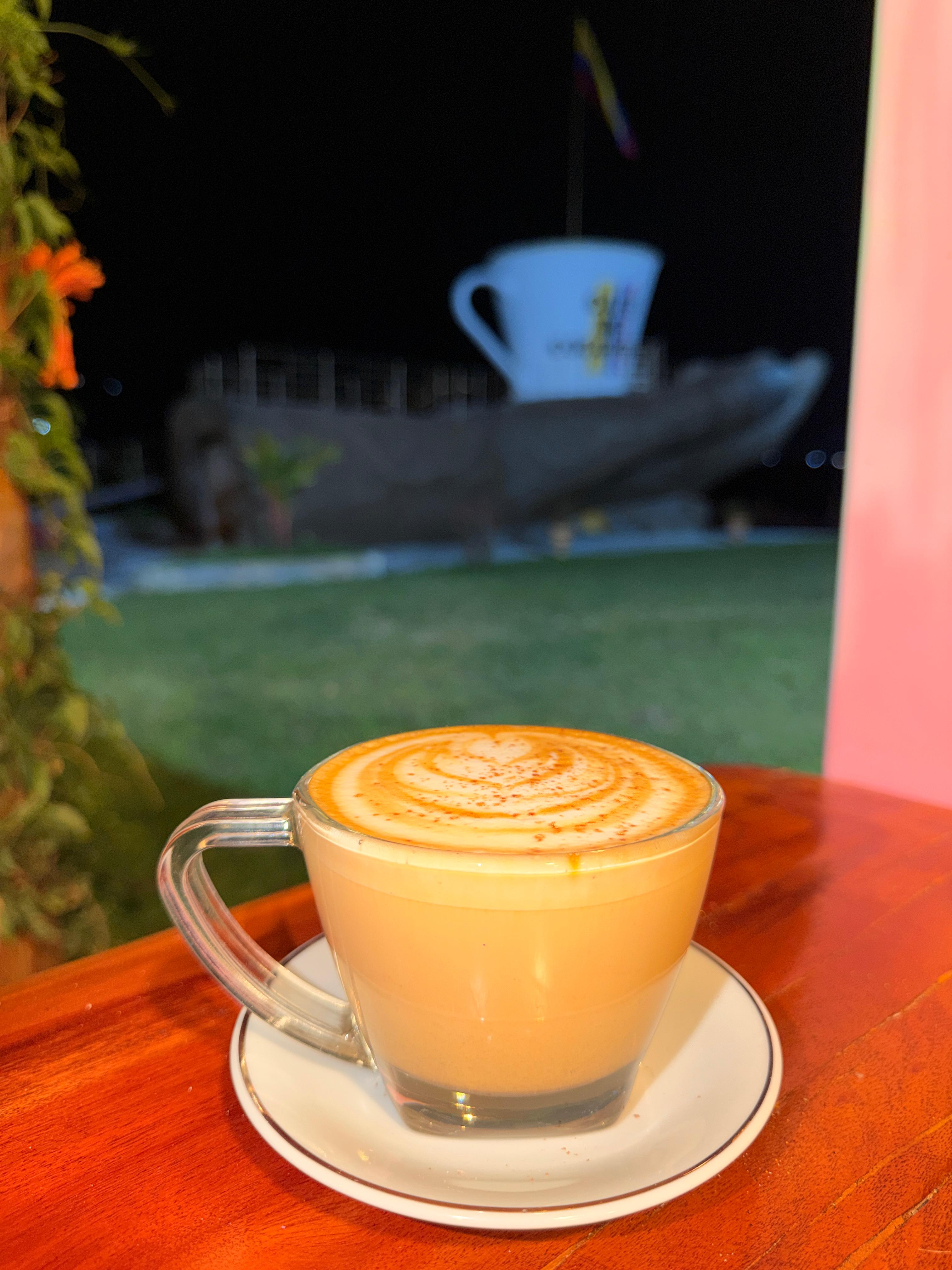 Capuchino con arte latte y la mano al fondo